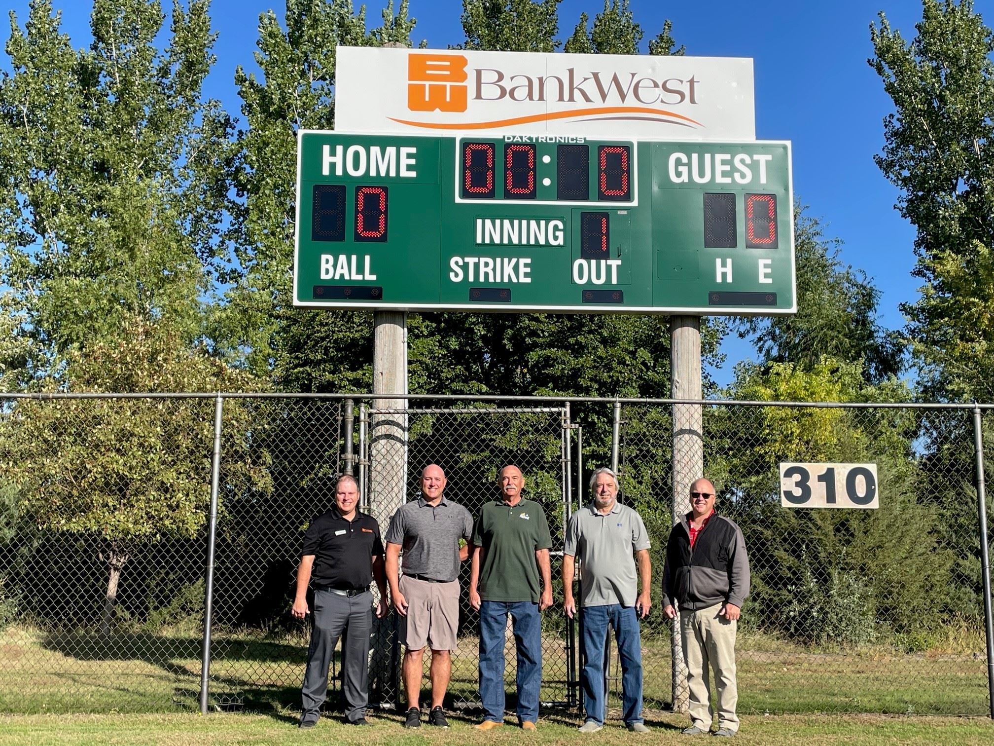 City, Bank, and Softball Assoc. reps in front of new scoreboard at Softball Complex